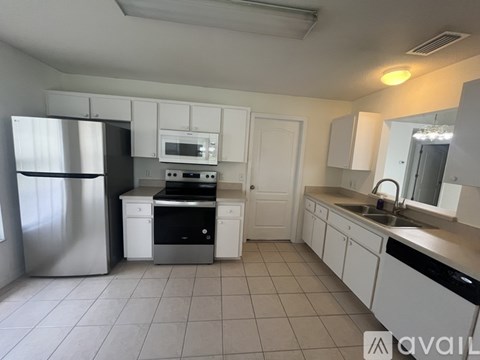 A kitchen with white cabinets and a stainless steel refrigerator.