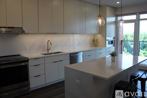 A kitchen with white cabinets and a marble backsplash.