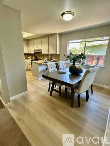 A kitchen with a dining table and chairs in the foreground.