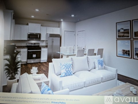 A modern living room with a white couch and a kitchen area in the background.