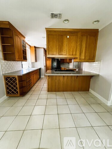 A kitchen with wooden cabinets and a tiled floor.