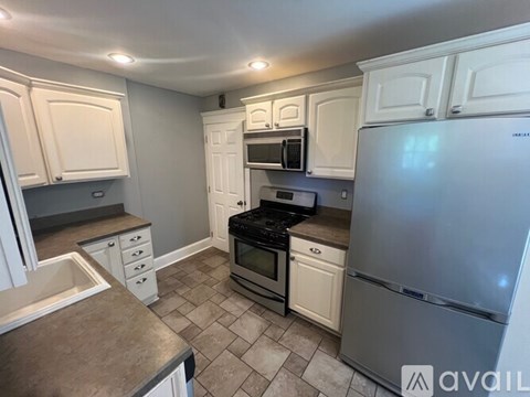 A kitchen with white cabinets and a refrigerator.