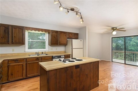 A kitchen with wooden cabinets and a stove top oven is for sale.