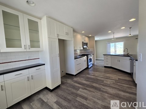 A kitchen with white cabinets and a wooden floor.
