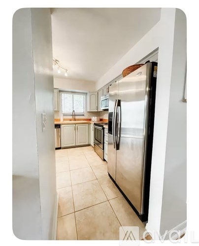 A kitchen with a refrigerator, sink, and oven.