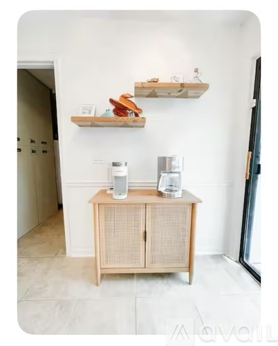 A wooden cabinet with a shelf above it holding various items.