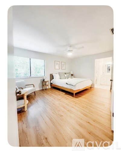 A bedroom with a bed, chair, and window.