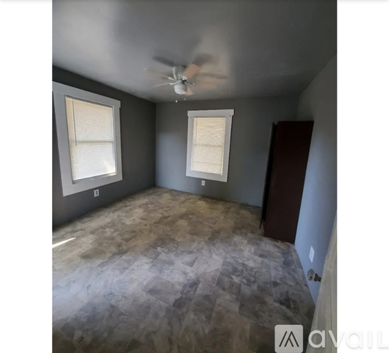 A room with a ceiling fan and two windows.