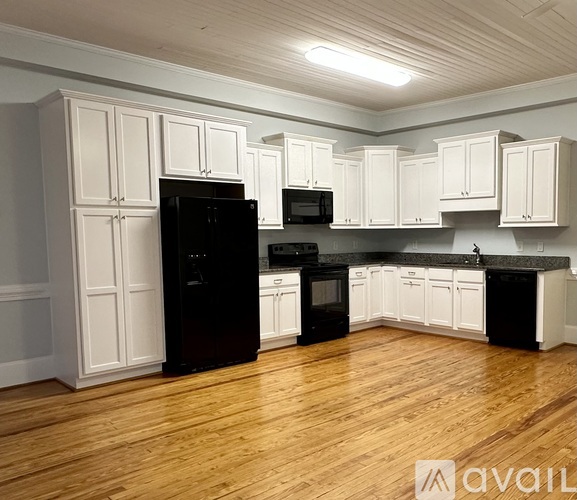 A kitchen with black appliances and white cabinets.