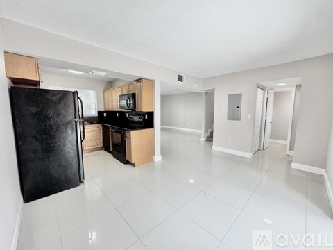 A kitchen with a black refrigerator and white tiled floors.