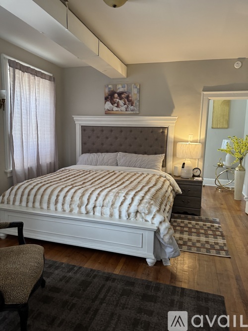 A bedroom with a large bed and a chair.