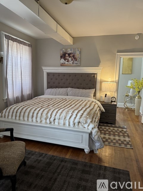 A bedroom with a large bed and a chair.