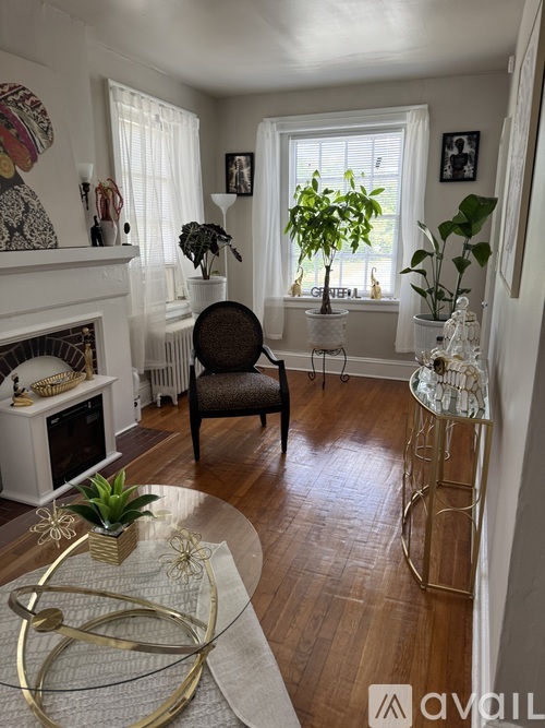 A living room with a fireplace, chair, and potted plants.