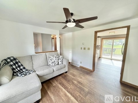 A living room with a grey couch and a ceiling fan.