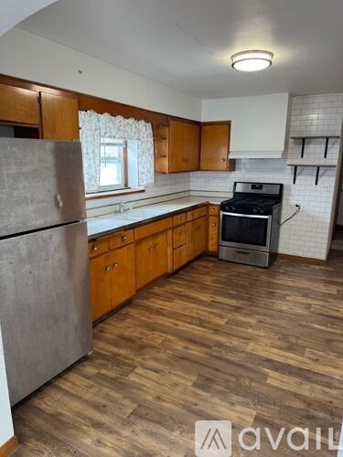 A kitchen with wooden floors and a stainless steel refrigerator.