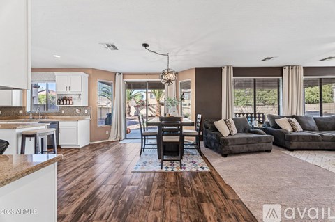 A living room with a brown floor and a dining area with a table and chairs.
