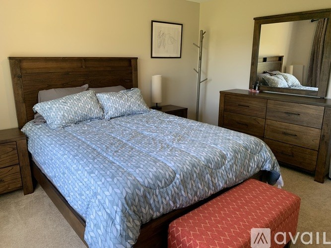 A bedroom with a bed, nightstand, and a mirror.