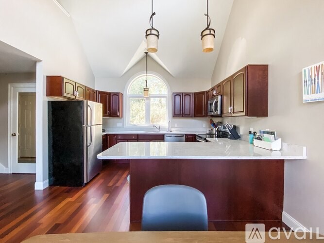 A kitchen with a black refrigerator and brown cabinets.