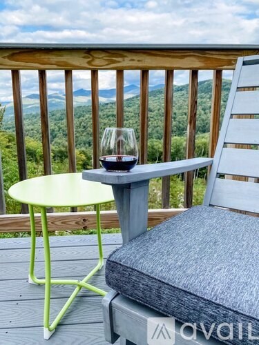 A table with a glass of wine on a balcony overlooking a forest.