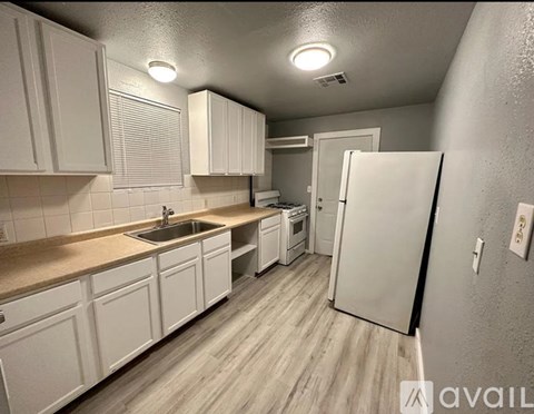 A kitchen with white cabinets and a white refrigerator.