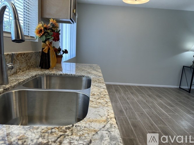A kitchen with a granite countertop and a stainless steel sink.