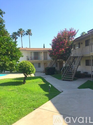 A building with a tree and bushes in front of it.