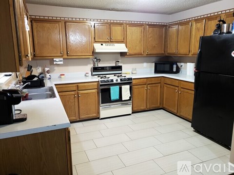A kitchen with wooden cabinets and a black refrigerator.
