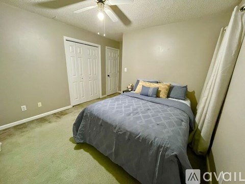 A bedroom with a bed, pillows, and a ceiling fan.