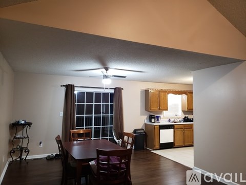 A kitchen with a table and chairs in the foreground and a counter with a sink in the background.