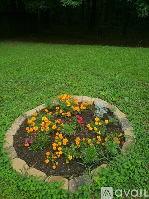 A flower bed with a variety of colorful flowers in the center of a grassy area.