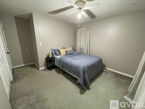 A bedroom with a bed, nightstand, and window.