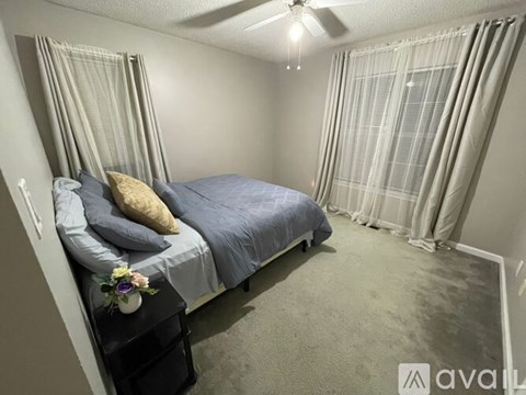 A bedroom with a bed, pillow, and a flower vase on a nightstand.