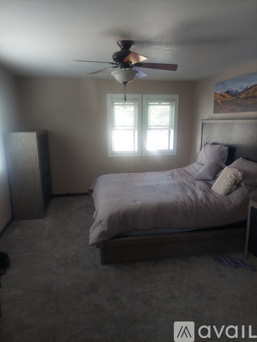 A bedroom with a bed, dresser, and window.