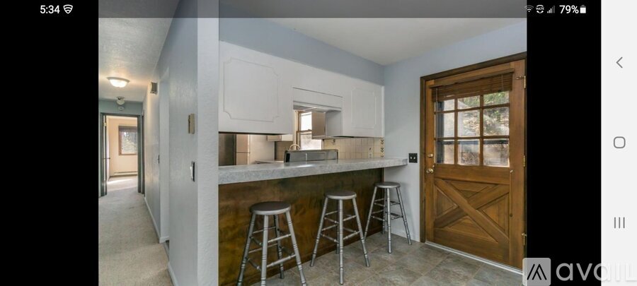 A kitchen with white cabinets and a wooden door.