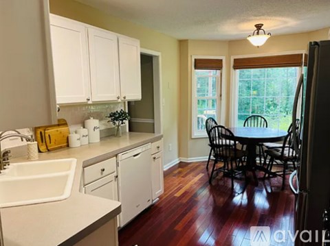 A kitchen with white cabinets and a wooden floor.