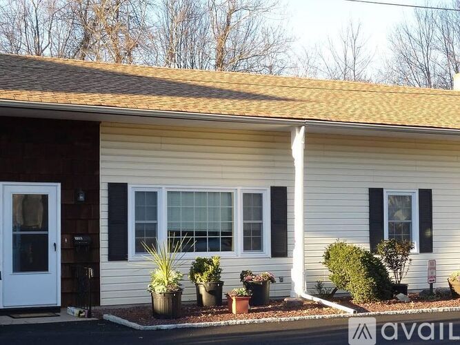 A house with a white door and black shutters is for sale.