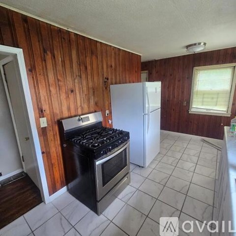 A kitchen with a black stove top oven and a white refrigerator.
