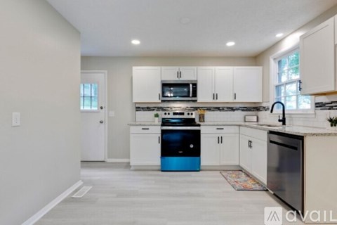 A kitchen with white cabinets and a blue dishwasher.