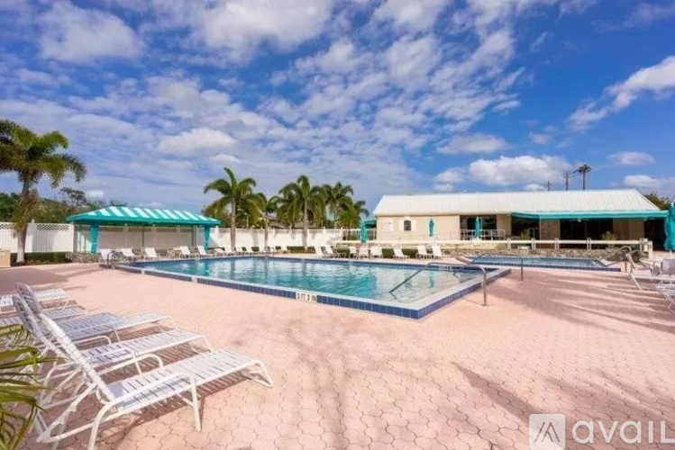 A pool area with sun loungers and a building in the background.