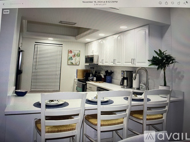 A white kitchen with a dining table set for two.