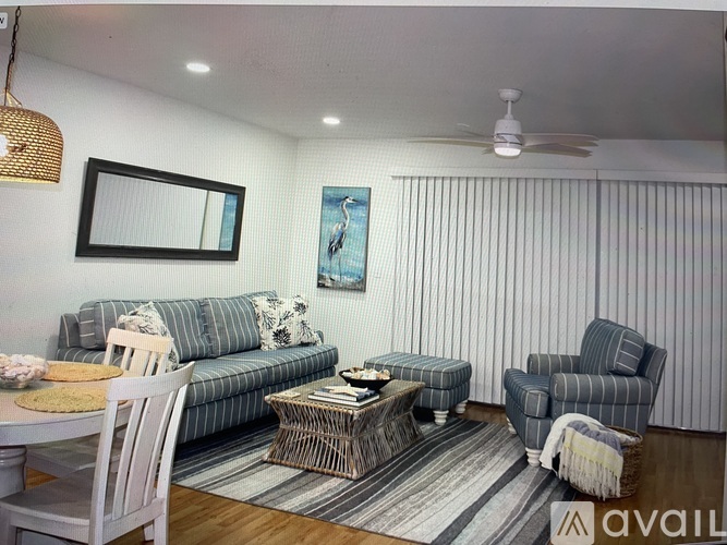 A living room with a grey couch, a grey armchair, a coffee table, and a dining table with chairs.