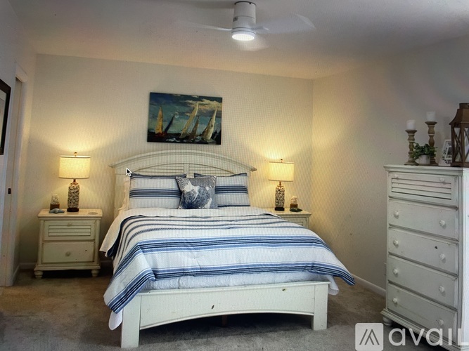 A bedroom with a bed, two nightstands, and a painting on the wall.