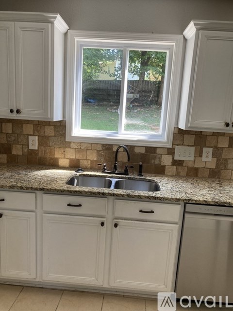 A kitchen with a sink and cabinets under a window.