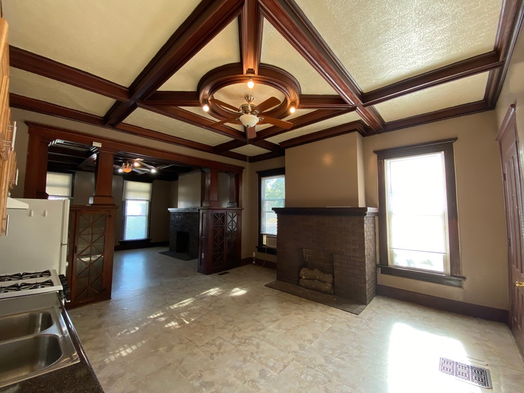 A large, empty room with a fireplace and a chandelier.