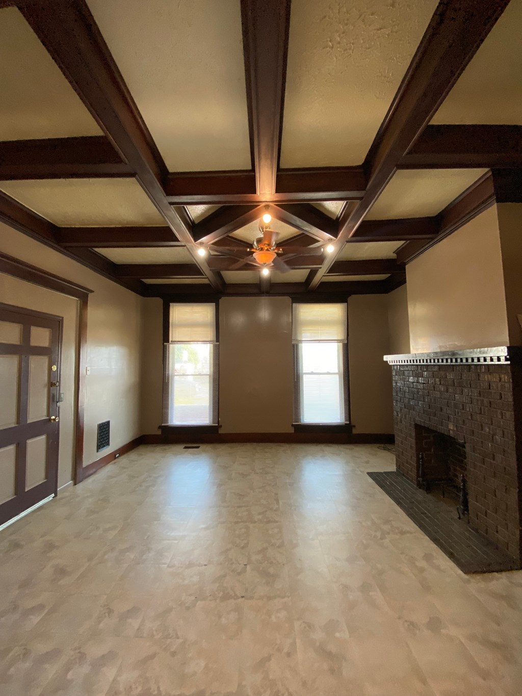 A large, empty room with a fireplace and wooden beams on the ceiling.