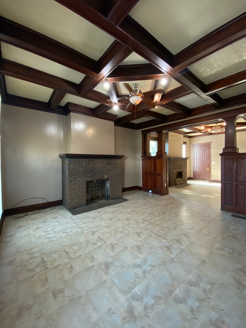 A large room with a fireplace and wooden beams on the ceiling.