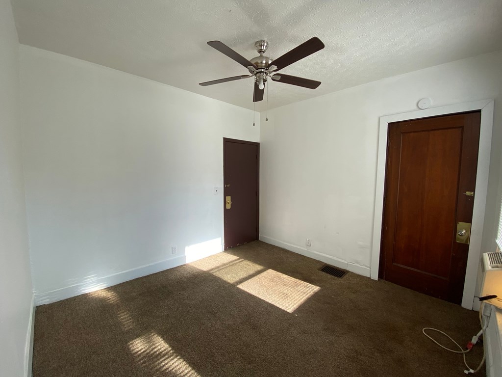 A room with a ceiling fan and two doors.