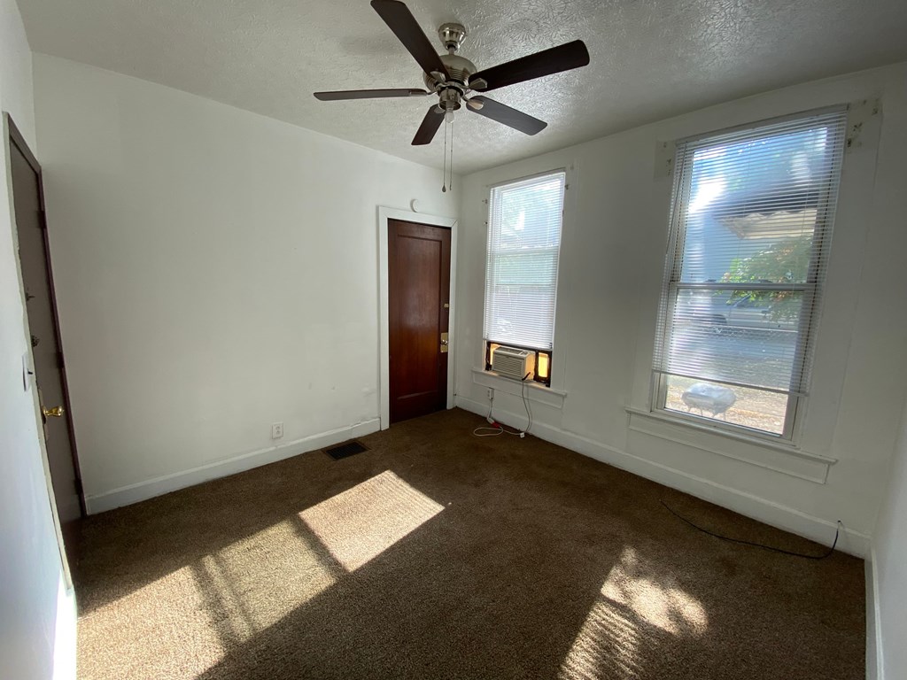 A room with a ceiling fan and a window with blinds.