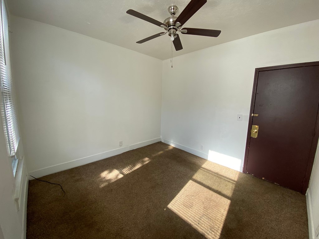 A room with a ceiling fan and a brown door.