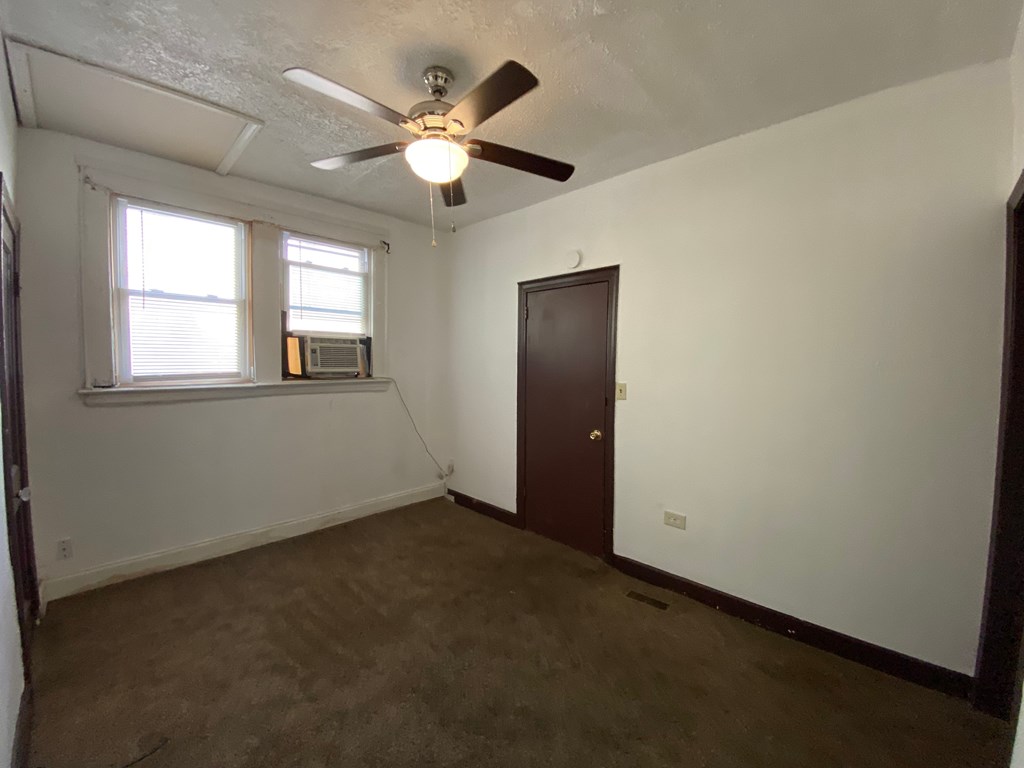 A room with a ceiling fan and a window.